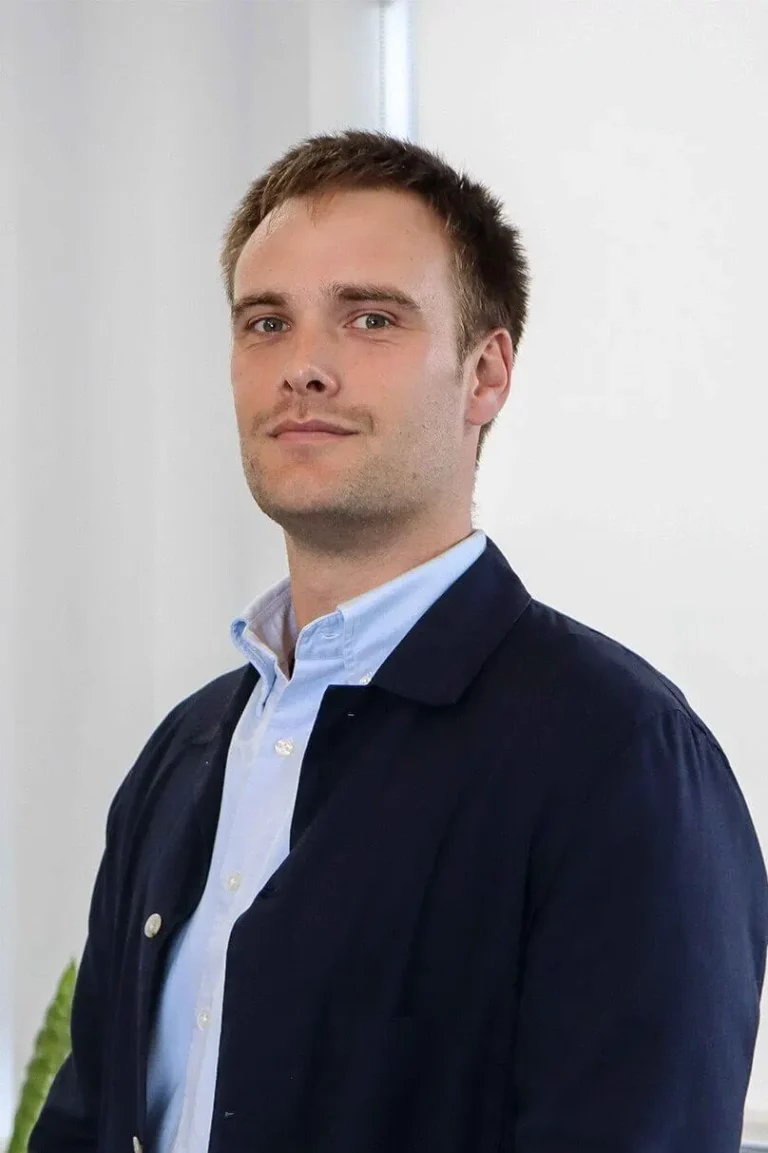 Portrait photo of Ed Dromgool, Design Manager stood in an open office