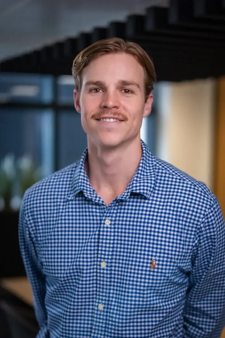Portrait photo of Joseph Cox, Project Manager stood in an open office